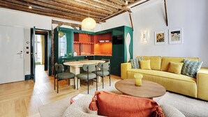 Un salon moderne avec un canapé jaune, une table basse ronde et un coin repas comprenant une table et des chaises.