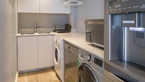 Eine kompakte Küche mit Waschmaschine, Geschirrspüler, Backofen und Wasserfiltersystem.
