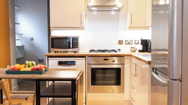 Een moderne keuken met roestvrijstalen apparatuur, een magnetron, oven en een koelkast.