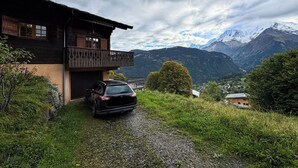 A chalet with a balcony, a gravel driveway, and a mountainous backdrop. - Chalet facing Mont Blanc, calm and comfort (Saint-Gervais-les-Bains)