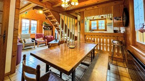 A wooden cabin interior with a dining area, kitchen, and living room. - Chalet facing Mont Blanc, calm and comfort (Saint-Gervais-les-Bains)