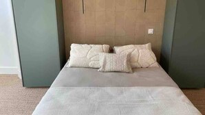 Une chambre à coucher avec un lit, deux lampes fixées au mur et un mur à texture.