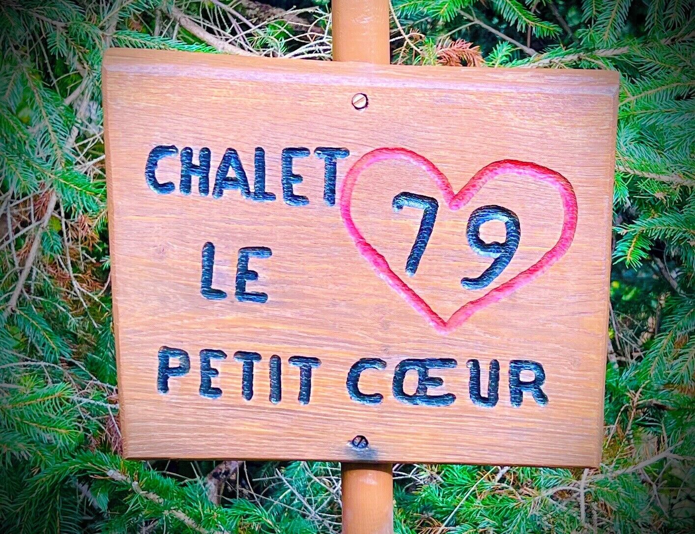 A wooden sign with the text "CHALET LE PETIT COEUR" and a heart with the number 79.
