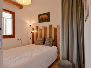 Cozy retreat with a neatly made bed, bedside lamp, and a mountain landscape painting above.