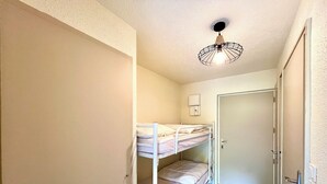 A room with bunk beds, a door, and a ceiling light fixture. - Le Refuge des Skieurs (Combloux)