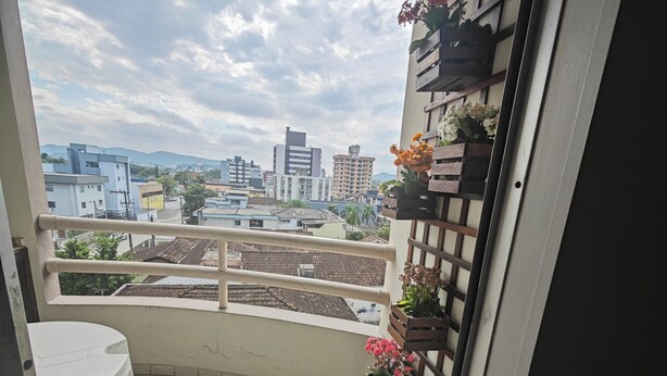 A balcony with a tiled floor, a white table, and potted plants.
