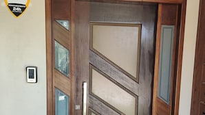 A wooden door with a glass panel and a keypad lock.