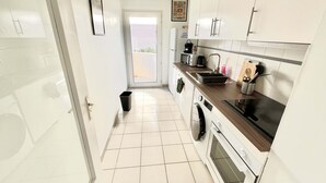 Cocina compacta con lavadora, microondas y lavamanos.