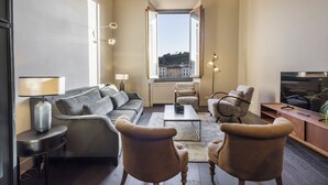 A modern living room with a sofa, armchairs, a coffee table, and a TV.