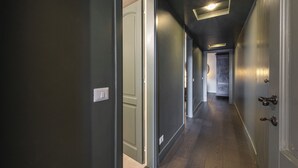 A hallway with dark walls, a wooden floor, and a ceiling light fixture.