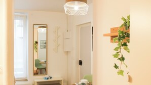 Une pièce lumineuse et bien éclairée, avec un plancher en bois, une table à manger entourée de chaises, un miroir et un luminaire suspendu.
