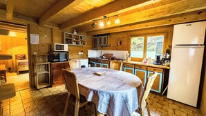 A cozy cabin-style kitchen with wooden walls and a dining table set for four. - Authentic family chalet with garden in Chamonix (Chamonix-Mont-Blanc)