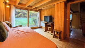 A wooden cabin room with a bed, a television, and a view of the outdoors. - Authentic family chalet with garden in Chamonix (Chamonix-Mont-Blanc)