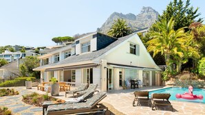 Een modern huis met een zwembad, terras en uitzicht op de bergen.