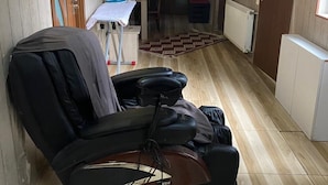 A room with a massage chair, a small table with a chair, and a radiator. - ARTISHA TRAVEL HOTEL (Tbilisi)