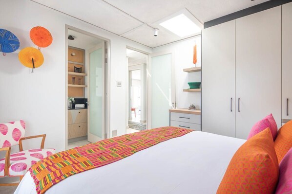 A bedroom with a bed, a wardrobe, a desk, and a chair. There are also two doors leading to other rooms.