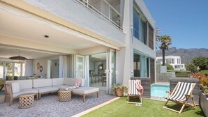 Een modern huis met een groot terras, buitenmeubilair en een zwembad.
