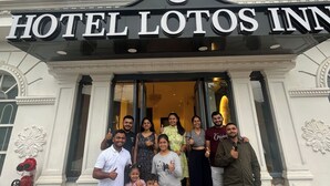 Eine Gruppe von Menschen steht vor dem Hotel Lotos Inn, das im klassischen Stil mit aufwendigen Details und einem markanten Eingangsbereich gestaltet ist.