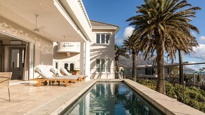 A poolside area with lounge chairs, a pool, and palm trees.