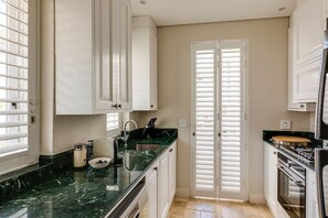 A kitchen with white cabinets, a black marble countertop, a sink, and a stove.