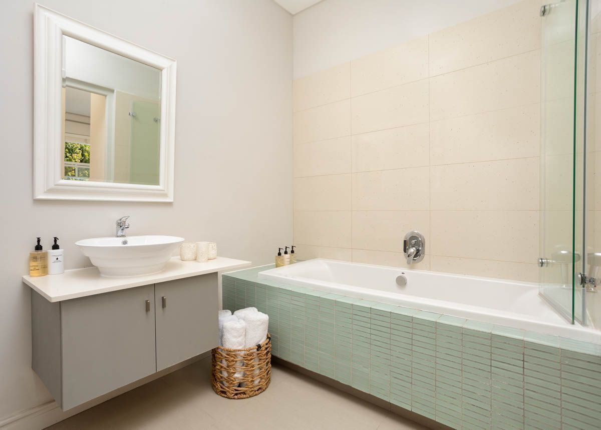 A modern bathroom with a freestanding bathtub, a large mirror, and a vanity with a sink and storage cabinets.