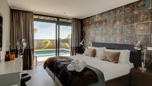 Una habitación de hotel moderna con una cama grande, vista a una piscina y una pared decorativa.