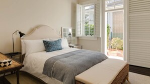 Une chambre à coucher avec un lit, une table de chevet, une lampe et une fenêtre avec des volets.