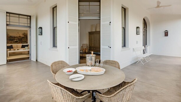 Un espace repas avec une table ronde, des chaises en osier et un buffet.