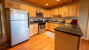 Una cocina con armarios de madera, un refrigerador, un microondas, un horno y una encimera de granito.