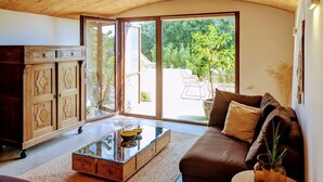 Una sala de estar acogedora con un aparador de madera, una mesa de centro de vidrio y un sofá marrón.