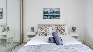 A modern hotel room with a large bed, a cityscape painting on the wall, and a glass door leading to a balcony. - Cozy London Apartment With 2 Bedrooms (London)