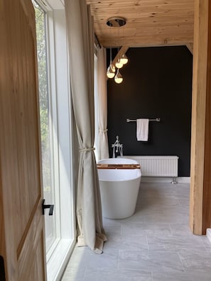 Un baño moderno con una bañera independiente, un perchero y un radiador.