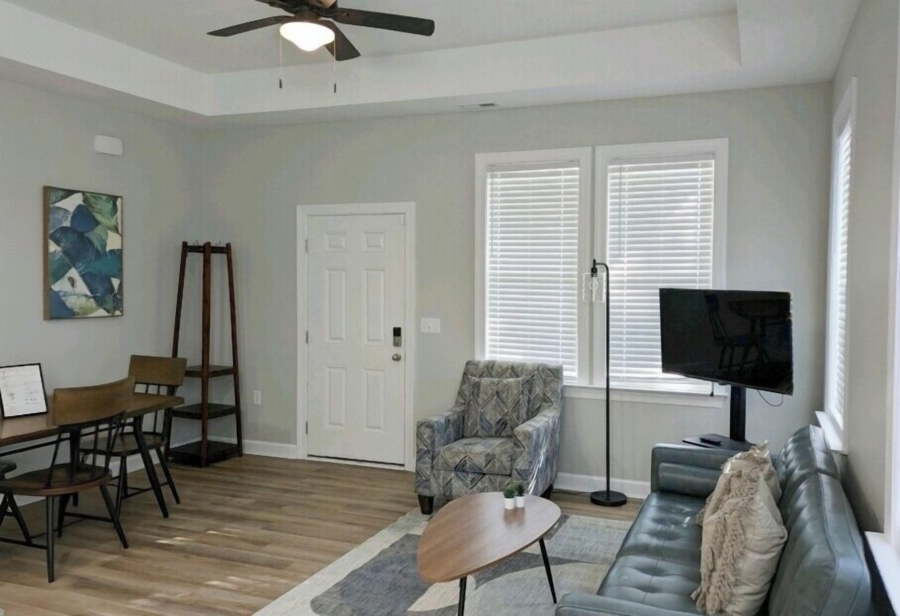 Un salon comprenant une table à manger, des chaises, un canapé, un téléviseur et un ventilateur de plafond.