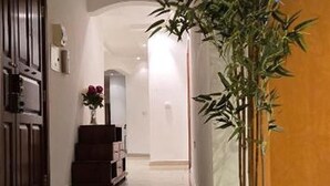 A hallway with a potted plant, a wooden door, and a staircase with a vase of flowers. - Large 4-bedroom apartment in fantastic Sliema: WiFi, AC -5 min to the Sea-  8ppl (Sliema)