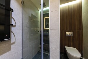 A modern bathroom with a glass shower enclosure, a toilet, and a built-in sink. - Woodside Apartment 218 (Raška)