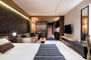 Una habitación de hotel moderna con una cama grande, un sofá, una mesa de comedor y un televisor.
