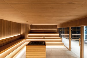 Un interior moderno con paneles de madera, una escalera central y un separador de vidrio.