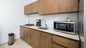 Eine moderne Küche mit Holzausstattung, einem Edelstahl-Spülbecken, einem Gasherd, einer Kaffeemaschine und einer Mikrowelle.