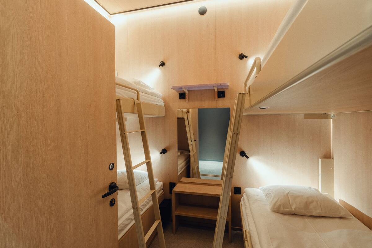 Une petite pièce en bois, avec des lits superposés, un petit bureau et un miroir.