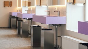 Eine Reihe moderner Waschbecken mit Spiegeln und Pendelleuchten in einer öffentlichen Toilette.
