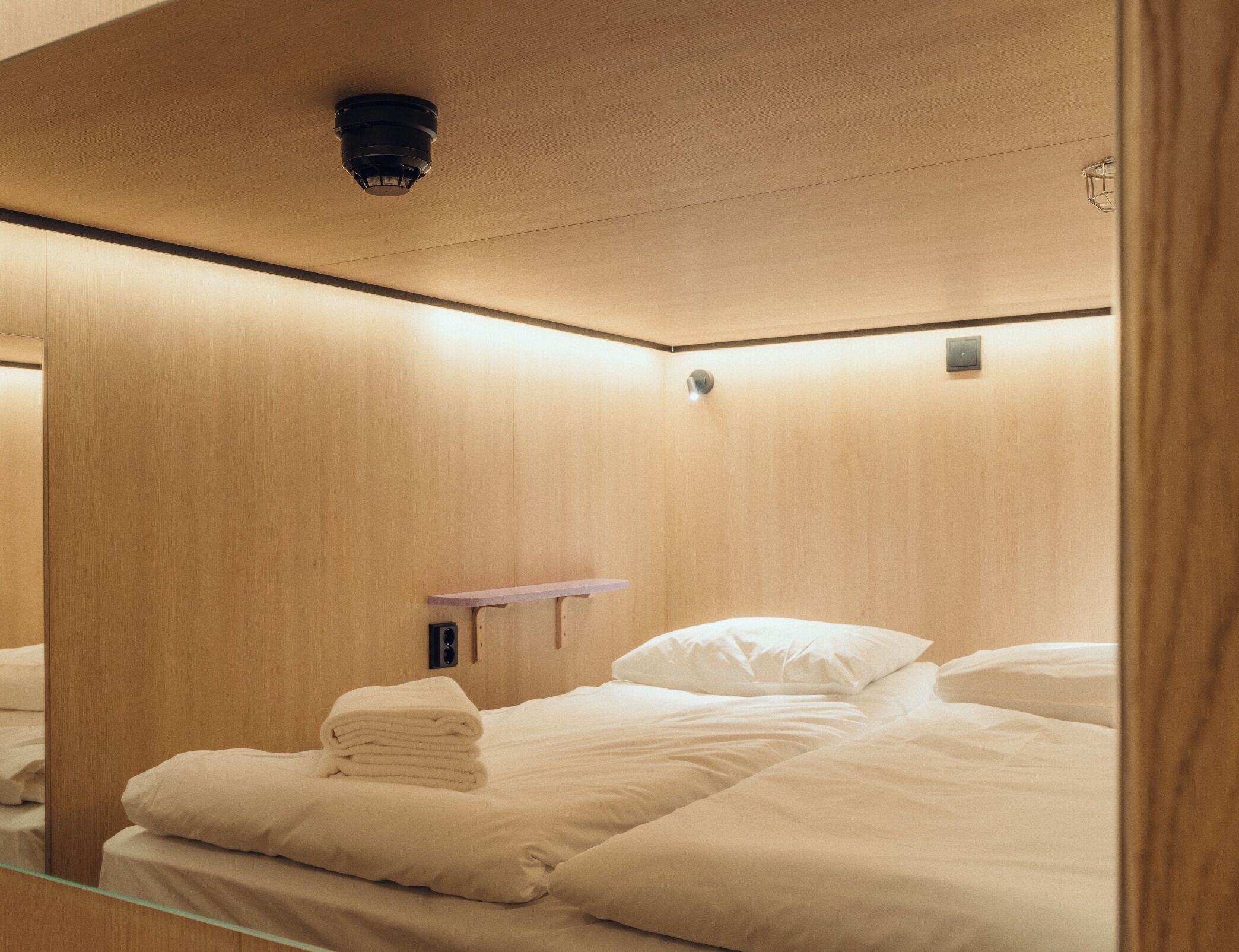 Een hotelkamer met een bed, een spiegel en een klein plankje.