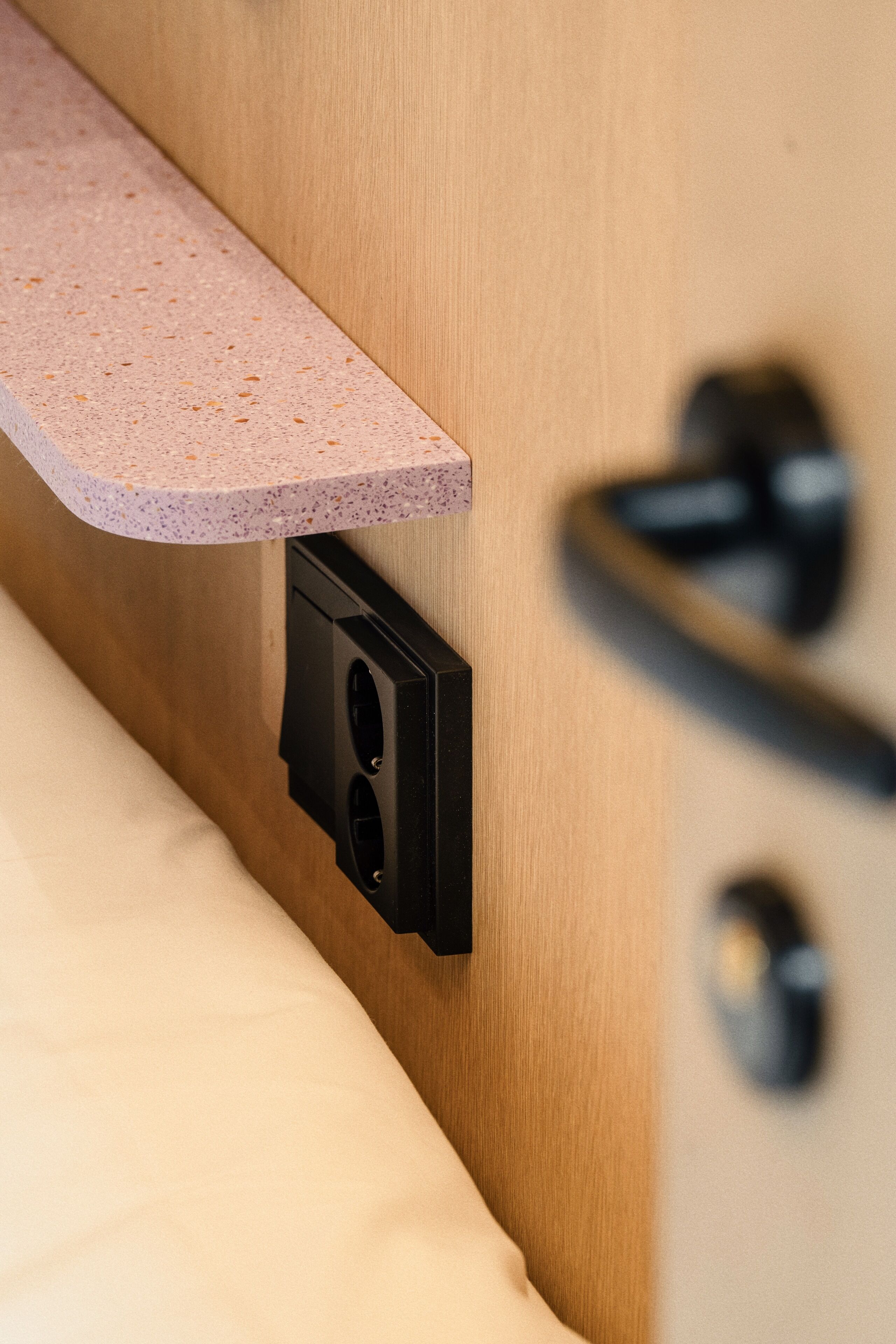 A close-up of a wooden door with a black handle and a pink speckled countertop.