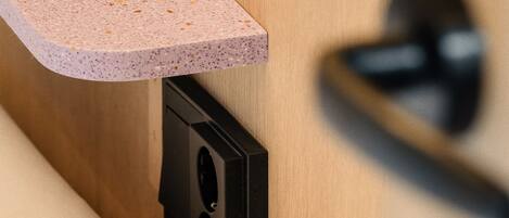 A close-up of a wooden door with a black handle and a pink speckled countertop.