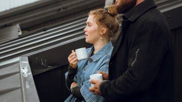Un uomo e una donna in piedi su un tetto, che tengono tazze bianche.