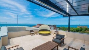 A rooftop terrace with a view of the sea, a round seating area, and a table. - Peninsula 8 𖢻3bd little peace of paradise𖢻5min walk Beach (Playa Langosta)