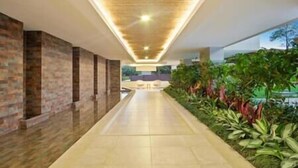A corridor with a tiled floor, brick walls on one side, and a row of plants on the other. - Peninsula 8 𖢻3bd little peace of paradise𖢻5min walk Beach (Playa Langosta)