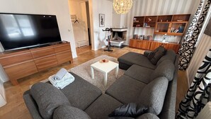 A modern living room with a large flat-screen TV, a sofa set, a coffee table, and a fireplace.