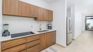 Une cuisine moderne avec des meubles en bois, un réfrigérateur en acier inoxydable, une machine à café et un mixeur.