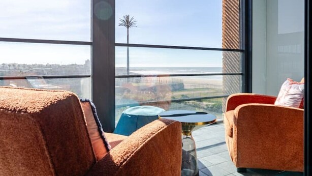 A balcony with two chairs and a small table, overlooking a cityscape. - Modern Ocean View Apartment - Pestana AnfaPlace (Casablanca)