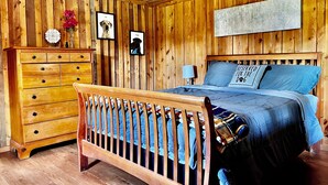 Un dormitorio con paneles de madera, una cama de madera, un aparador y una lámpara de pared.
